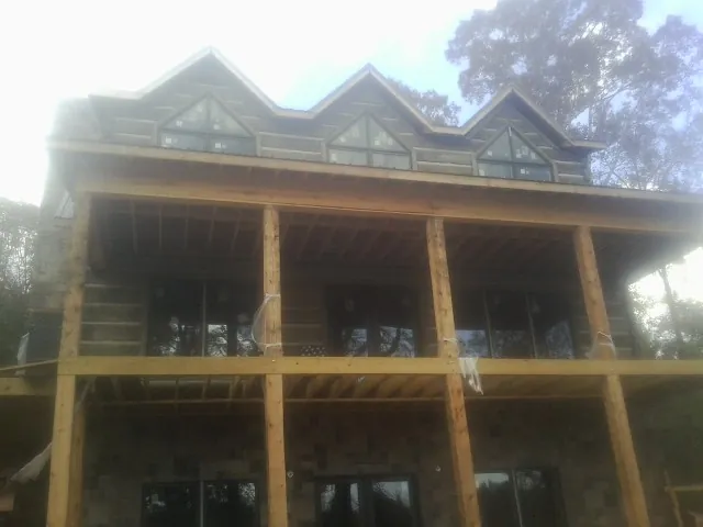 Dormers and porch framing on a large log home under construction — Roof Coating work by our crew in Atlantic Beach