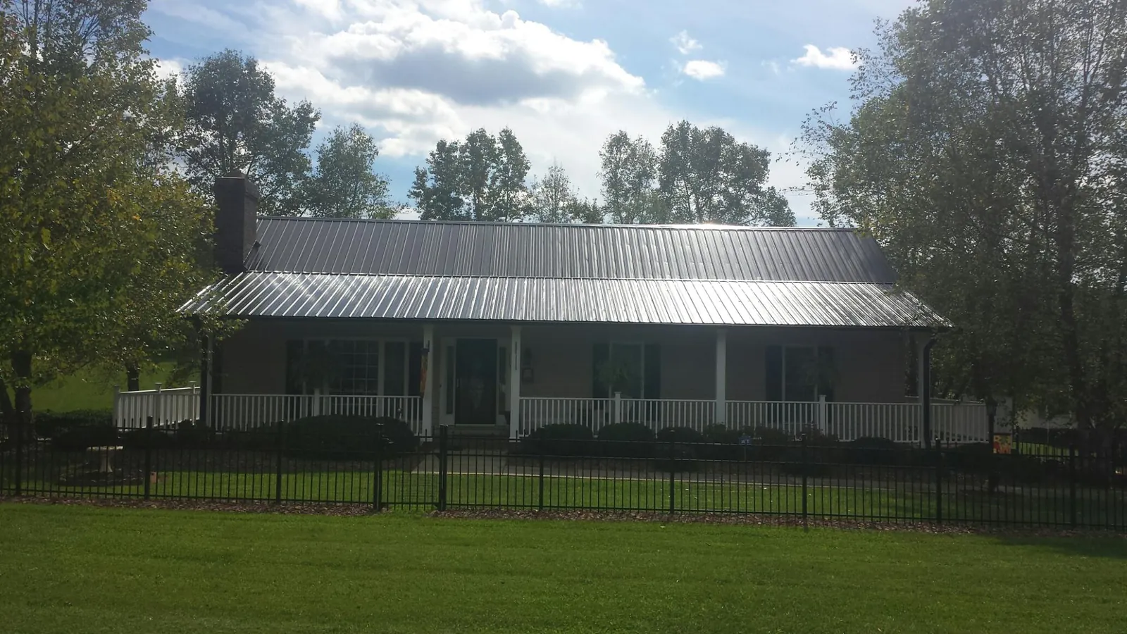 Gray metal roof on a brick ranch with a full width front porch — Gutter Guard Installation work by our crew in Atlantic Beach