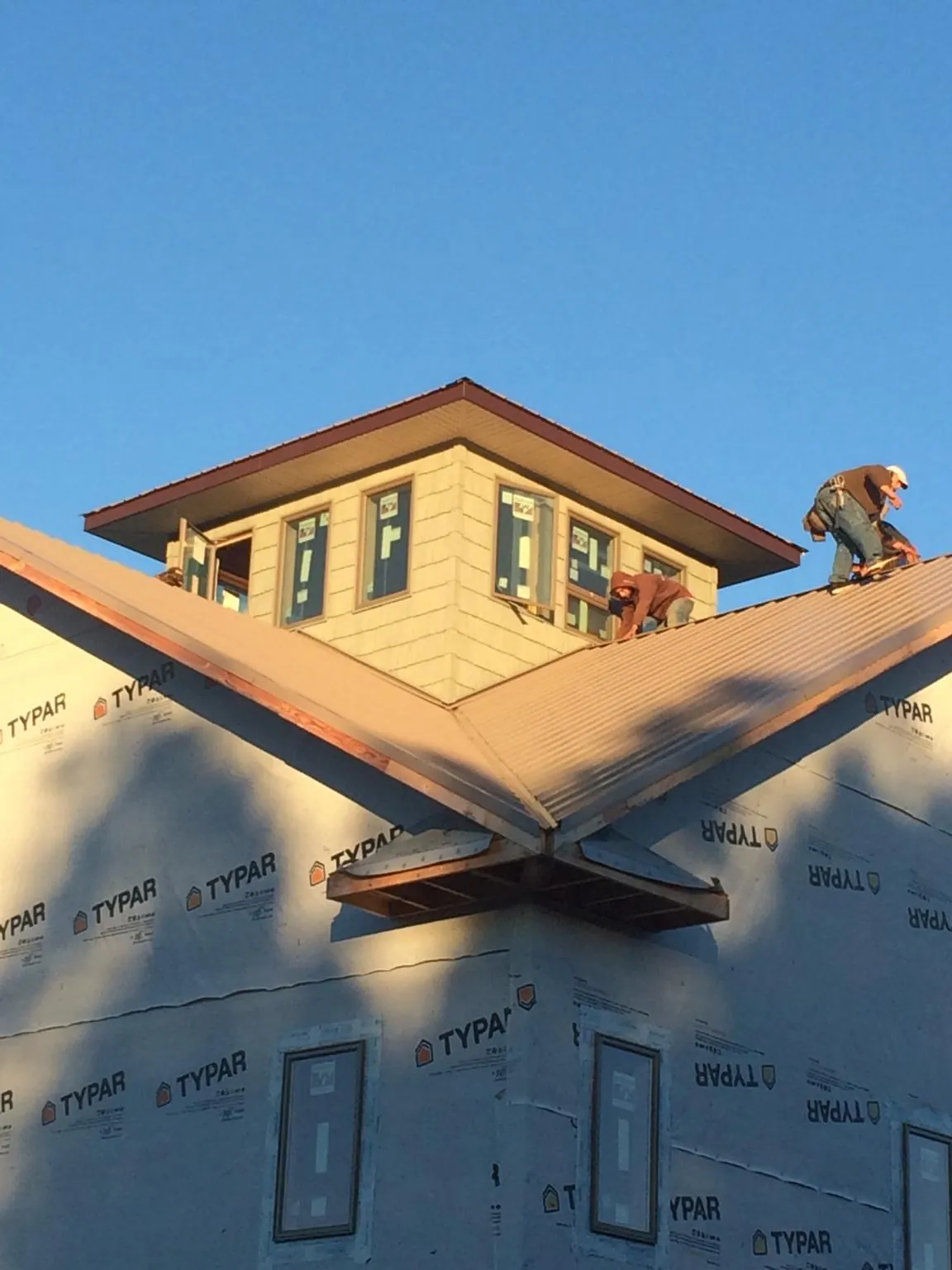 Roofers working around a rooftop cupola on a new metal roof at sunset — Roof Waterproofing in Atlantic Beach by Roofing Brothers